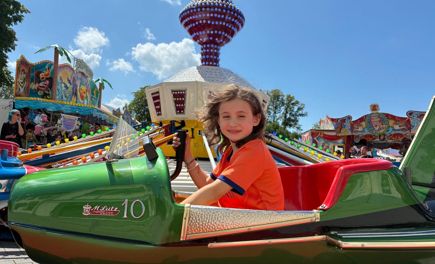 A child enjoying a colorful ride at an outdoor school carnival or community fair